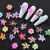 A collection of colorful floral resin nail charms shaped like hibiscus flowers displayed on a dark background.