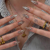 Close-up of hands displaying red pink striped press-on nails with a polka dot design on an almond shape