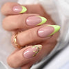 A hand displays press-on false nails with a nude base and yellow-green wavy accents on the tips.
