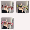 A set of cat eye reading glasses in red and yellow frames shown being held by a hand.