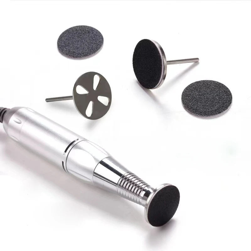 Un outil portable argenté avec disques de ponçage remplaçables pour les soins des pieds, à côté de plusieurs disques de ponça