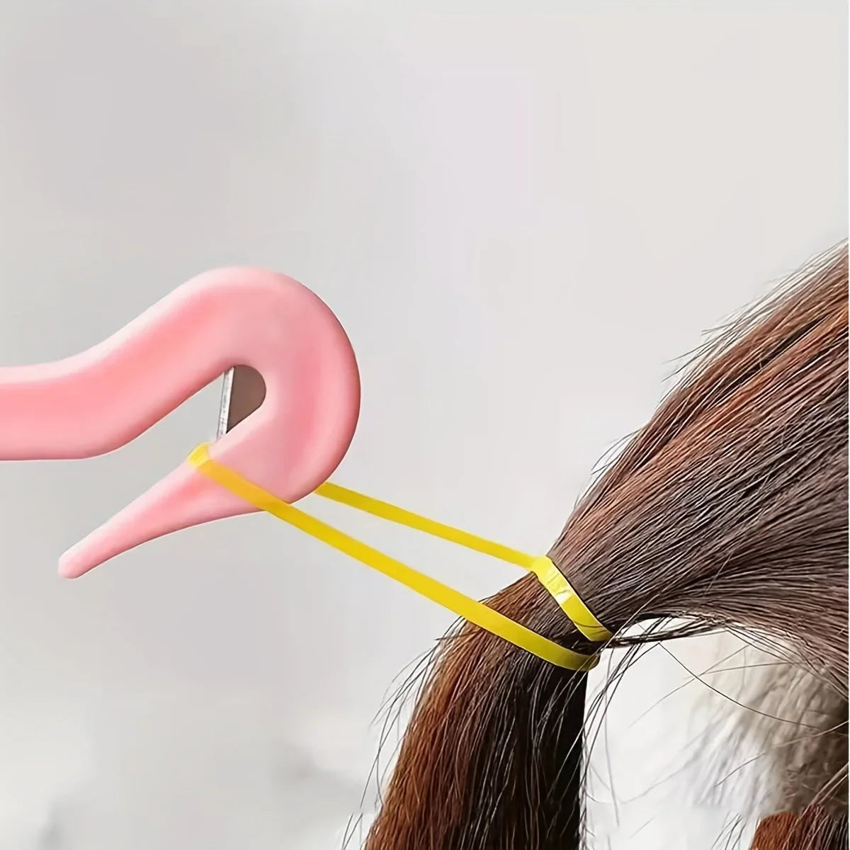 A pink hair styling tool is shown next to a strand of brown hair, demonstrating the kit's components.