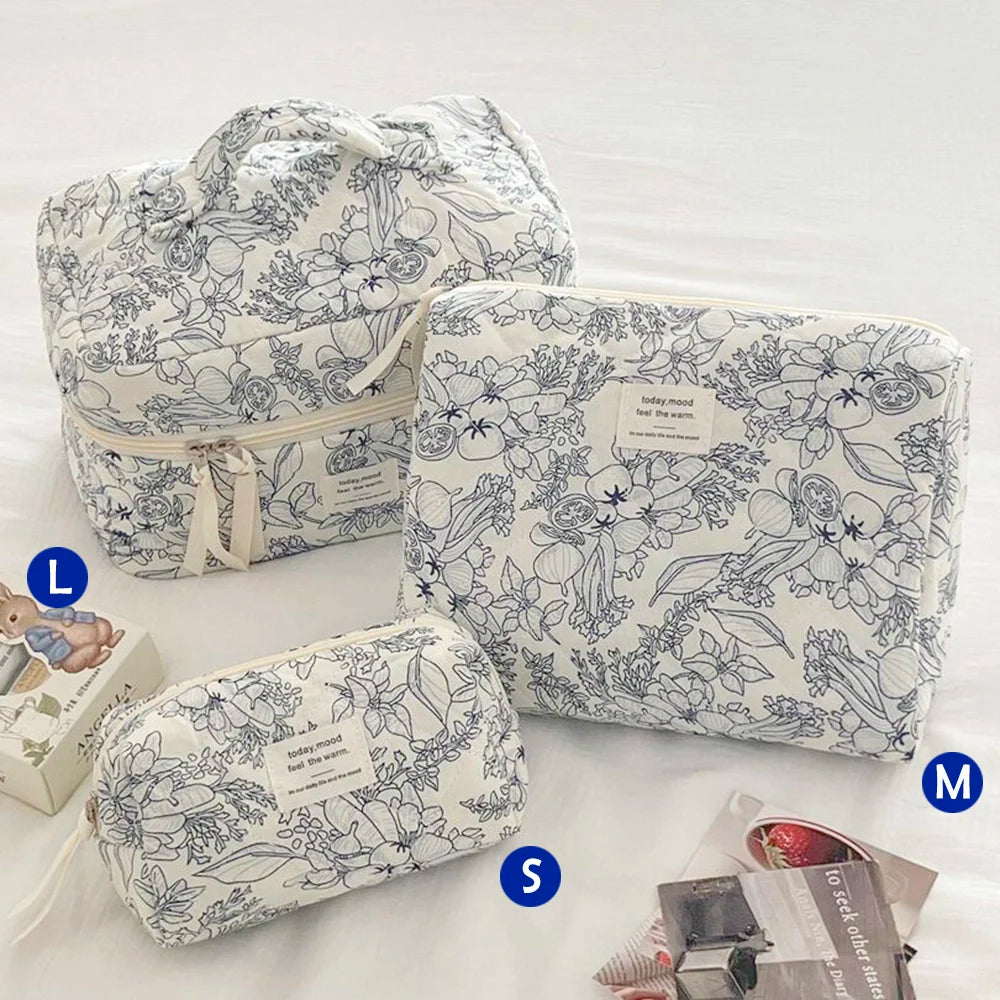 Three quilted cotton makeup bags in white and gray floral patterns are displayed on a white surface.