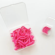 Un recipiente de plástico transparente contiene 30 almohadillas reutilizables de curvaca para pestañas de silicona rosa brill