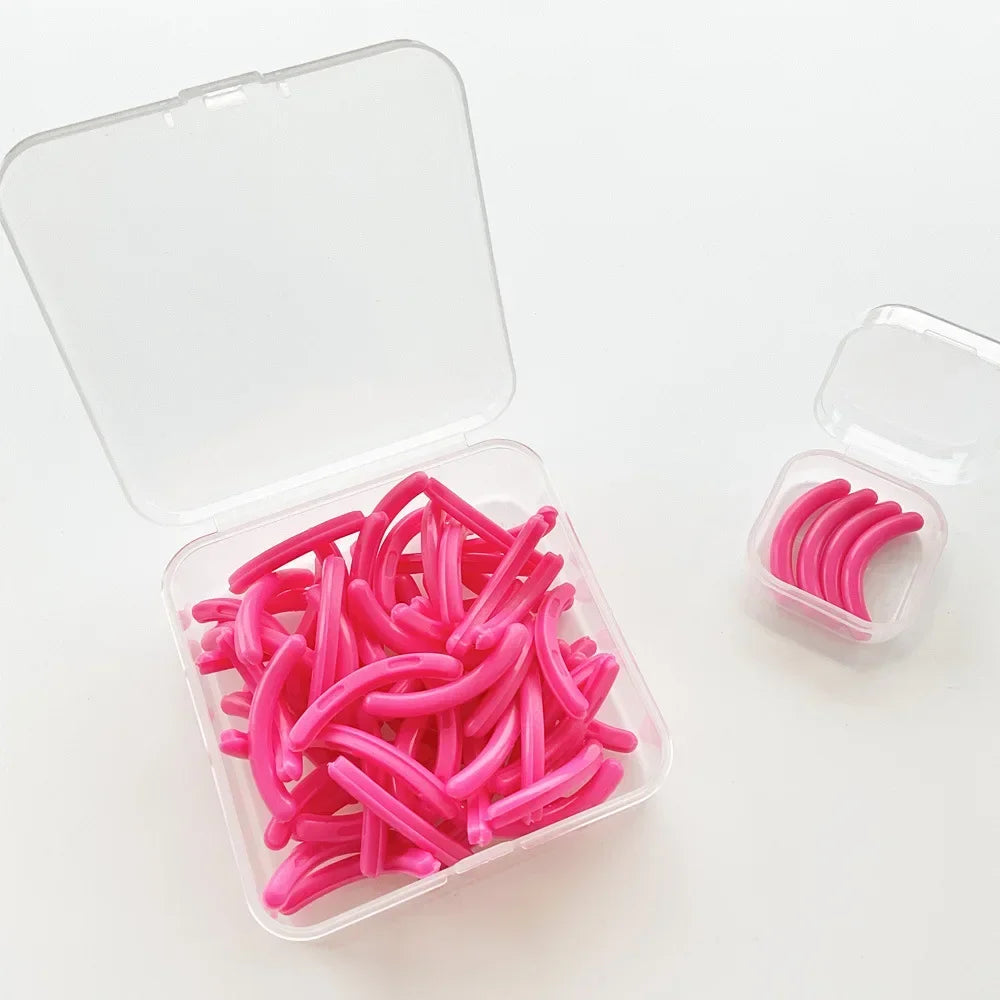 A clear plastic container holds a 30 count of bright pink reusable silicone eyelash curler pads.