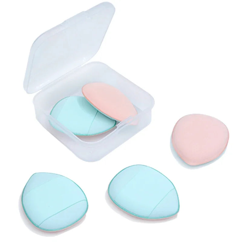 Un récipient en plastique transparent contenant trois éponges de fond de teint miniatures roses et bleues pour un maquillage 