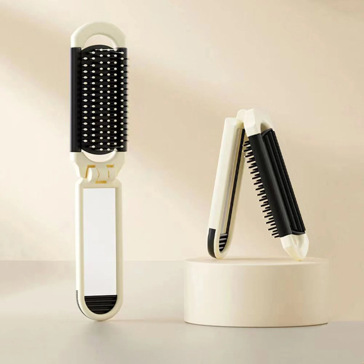 A white folding pocket hair comb with a mirror and scalp massage cushion displayed on a light surface.