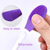 A purple silicone facial brush set with a detachable white handle and a purple exfoliating head being held by a hand.
