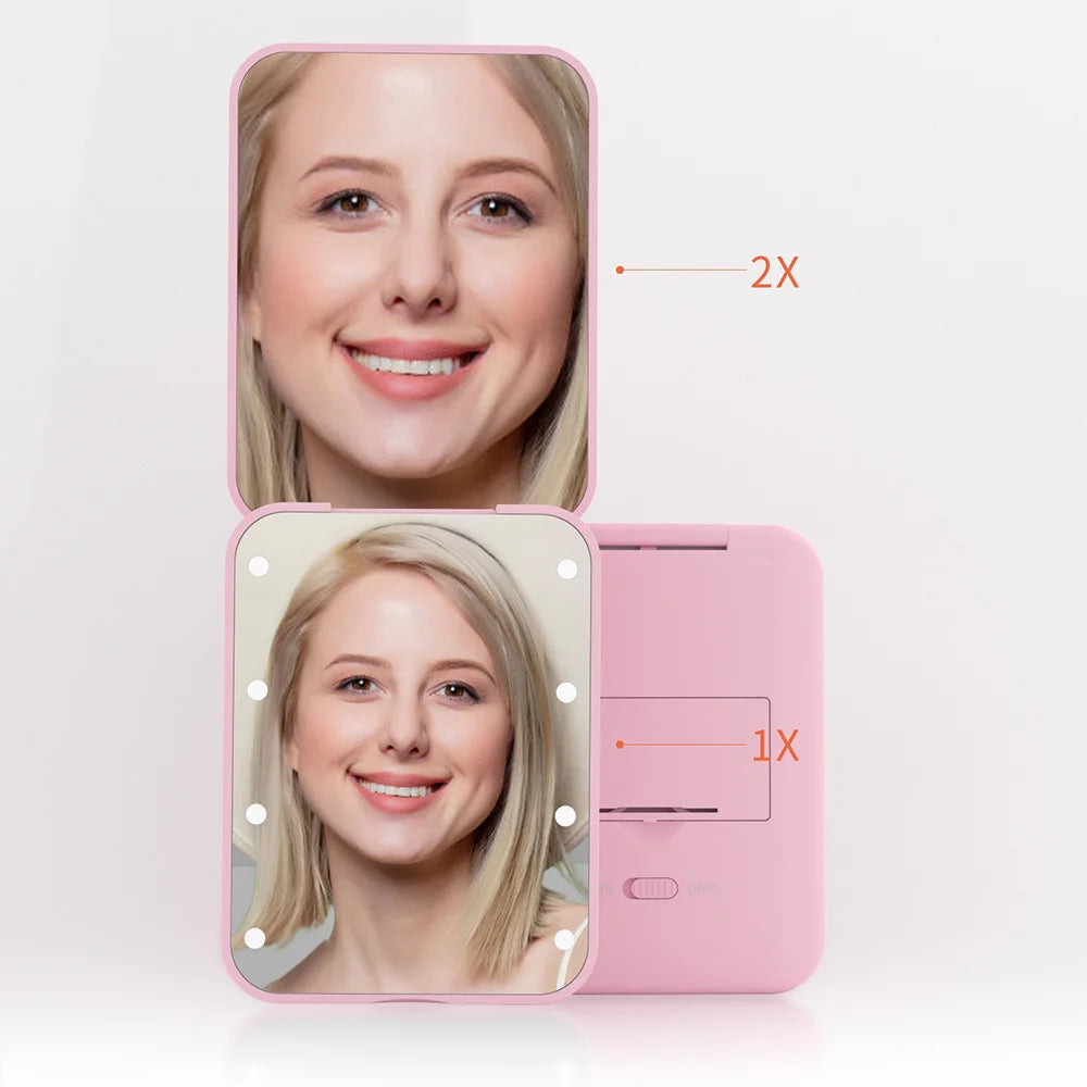 A pink portable LED magnifying makeup mirror showing a woman's face with magnification indicators.