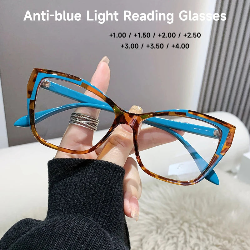A hand holds a pair of orange-tinted cat eye reading glasses with blue accents against a white background.