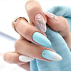 A hand displays press-on false nails with a light blue French wavy design on the index and middle fingers.