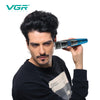 A man is holding a blue VGR electric beard and hair trimmer device up to his face.