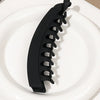 A black banana hair clip is shown resting on a white plate.