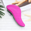 A bright pink classic detangling hair brush lying on a white surface next to a piece of paper and a hand.