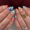 Gros plan d'une main montrant un ensemble de faux ongles à presser français roses avec différents motifs de paillettes et flo