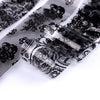 Gros plan de autocollants en feuille translucide à paillettes noir et blanc, montrant des motifs floraux complexes.