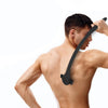 A man is using a black multi-layer silicone back shaver razor on his upper back.
