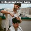 A man is using a comb to style the hair of a younger boy in an outdoor setting.