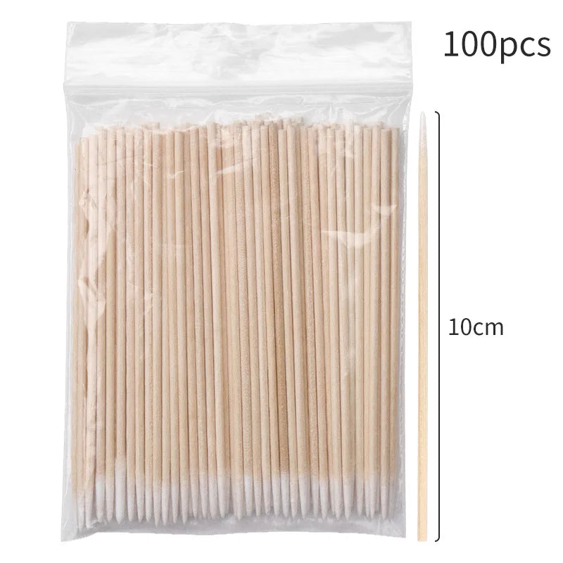 Un paquet de 100 brosses pour nettoyer et prolonger les cils, montré à côté d'une règle pour l'échelle.