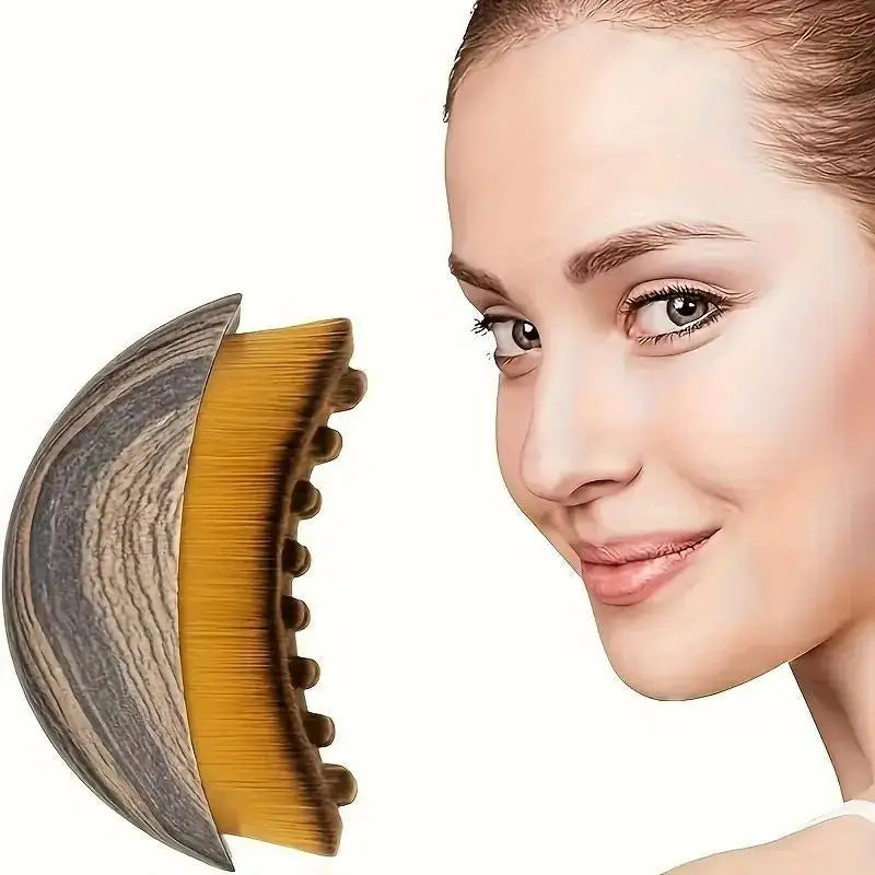 A close-up of a natural-bristle face brush showing its curved shape and golden bristles against a light skin tone.