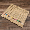 A collection of eco-friendly bamboo toothbrushes in various colors and designs laid out on a wooden surface.