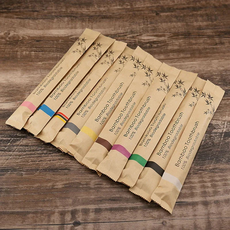 A collection of eco-friendly bamboo toothbrushes in various colors and designs laid out on a wooden surface.