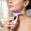 A woman is using a white face and neck massager with purple LED light therapy on her neck.