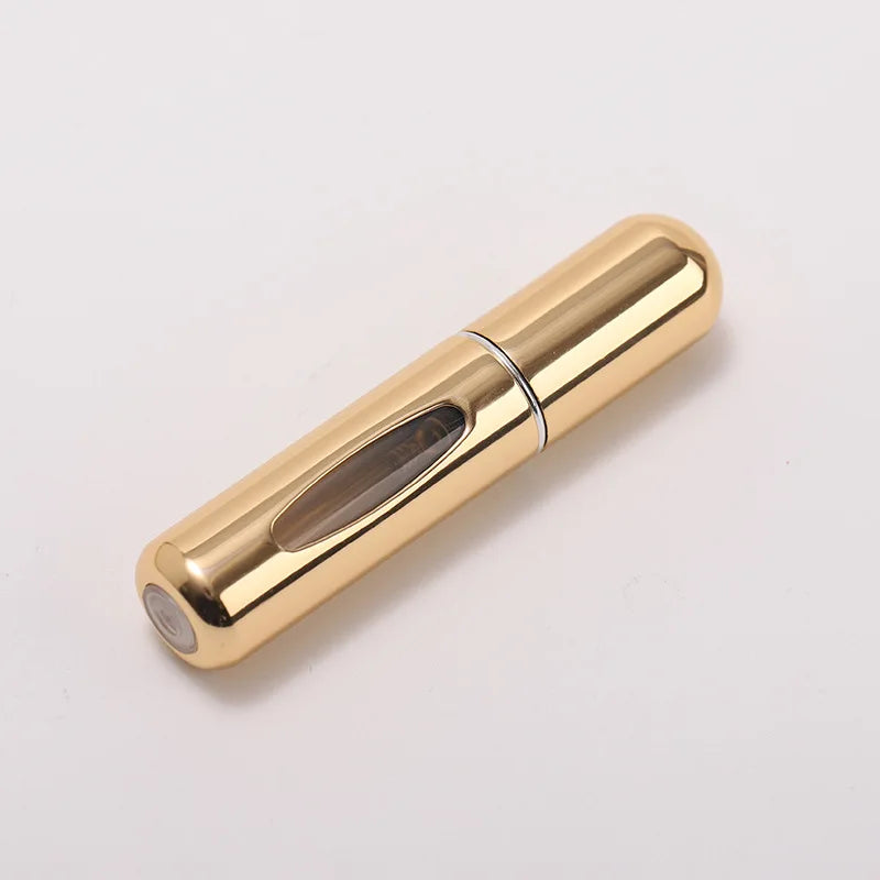 A gold-colored portable refillable perfume bottle with a clear glass insert.