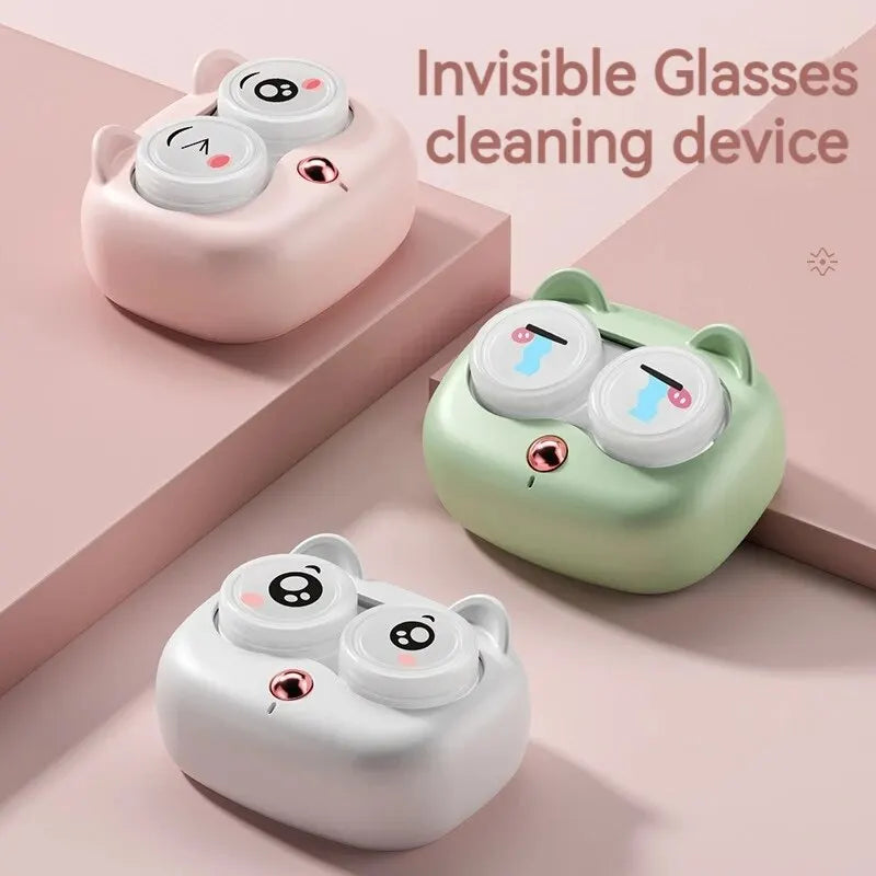 Three silicone cleaning devices for contact lenses in pink, green, and white on a light pink surface.