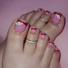 A close-up of a hand displaying press-on fake nails with pink and red accents and white floral designs.