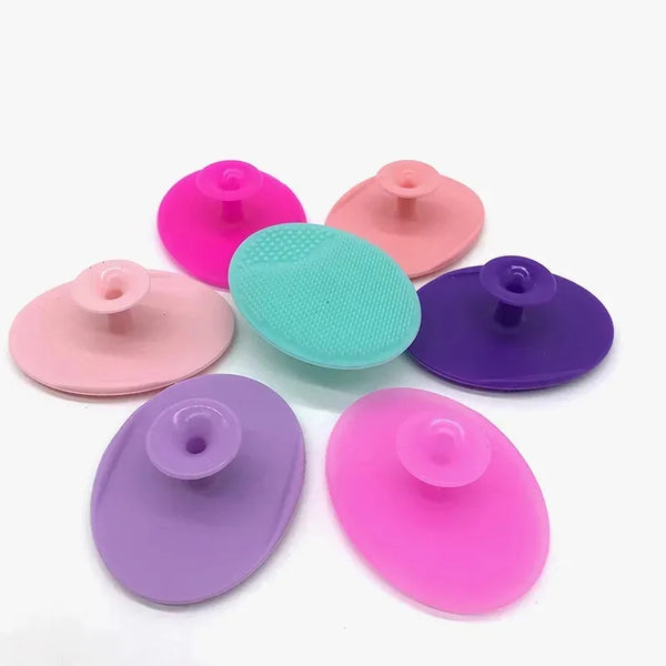 A collection of pink and purple silicone facial cleansing brushes with various dome shapes.