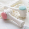 A white double-sided silica gel facial brush with pink and blue bristles is shown on a white background.