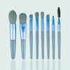 A set of various makeup brushes and sponges in shades of gray and blue displayed vertically.