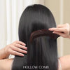 Eine Hand benutzt eine braune hohle Bürste, um langes, glattes schwarzes Haar von hinten zu stylen oder zu massieren.