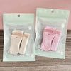 A set of pink beauty makeup tools including eyelash curlers packaged in clear plastic bags.
