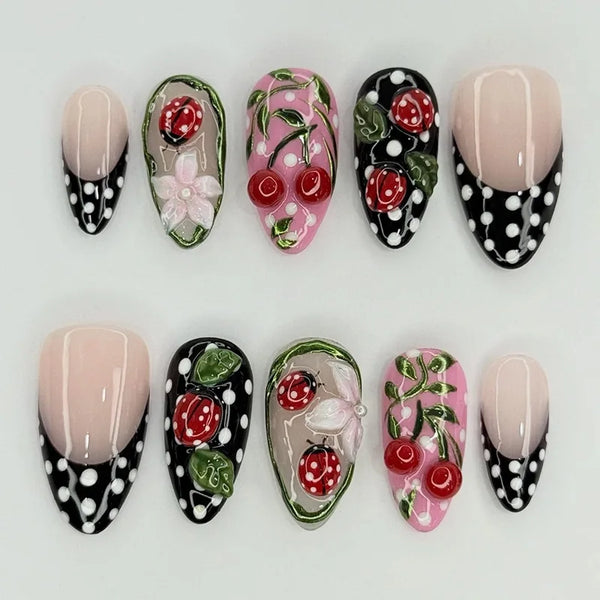 A set of press-on false nails in almond shape featuring a pink and black polka dot design with ladybug accents.