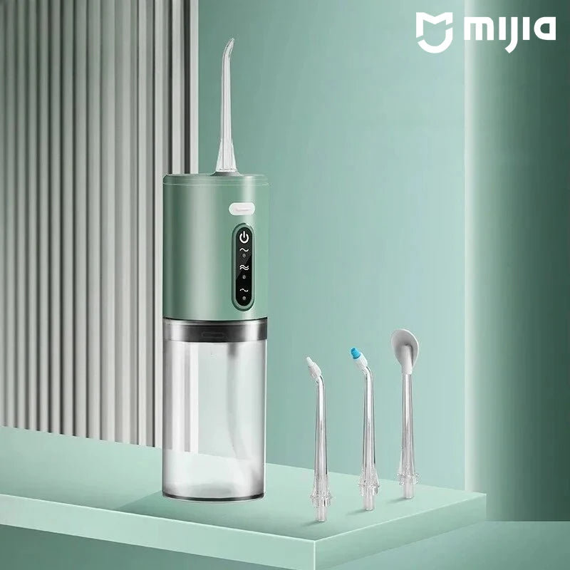 A portable electric water flosser in a mint green and clear design is shown on a light surface.