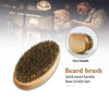 A beard brush with a solid wood handle and boar bristle hair shown next to an oval wooden handle.