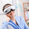 A woman wearing a white portable Bluetooth eye massager with vibration and music, smiling.