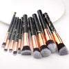 A set of ten professional makeup brushes with black handles and gold ferrules displayed on a white background.
