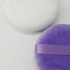 A purple jumbo soft powder puff for flawless makeup application is shown against a white background.