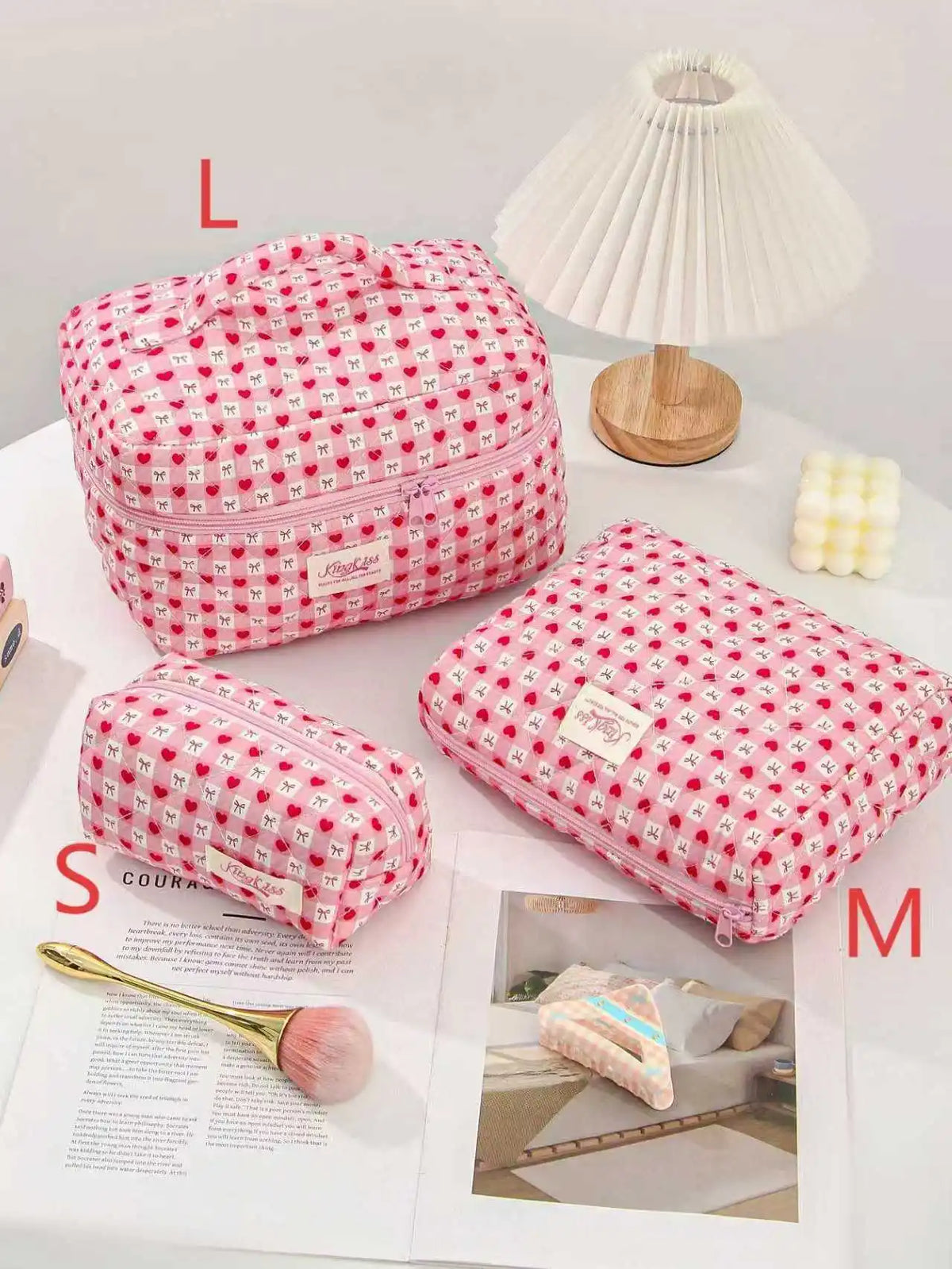 Pink quilted cotton makeup bag with a red floral pattern displayed next to a white lamp.