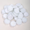 Una colección de esponjas o puffs de maquillaje blancos y esponjosos esparcidos sobre un fondo claro.