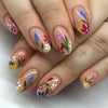 Gros plan d'une main montrant un ensemble de faux ongles à presser roses décorés de motifs floraux colorés.