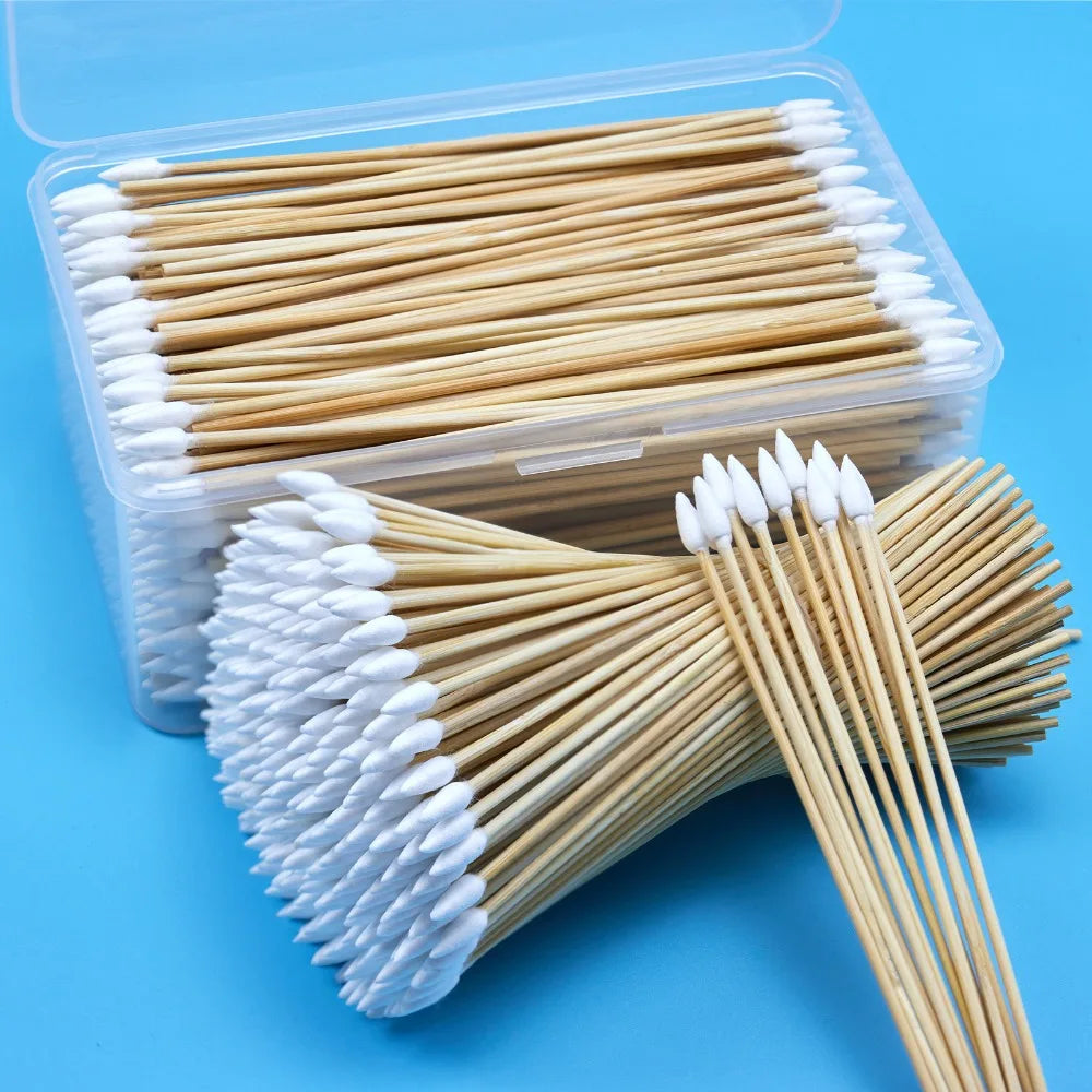 Un récipient en plastique transparent contient de nombreux cotons-tiges à manche en bois avec des pointes blanches.