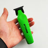 A hand holds a bright green hair clipper with a black comb attachment.