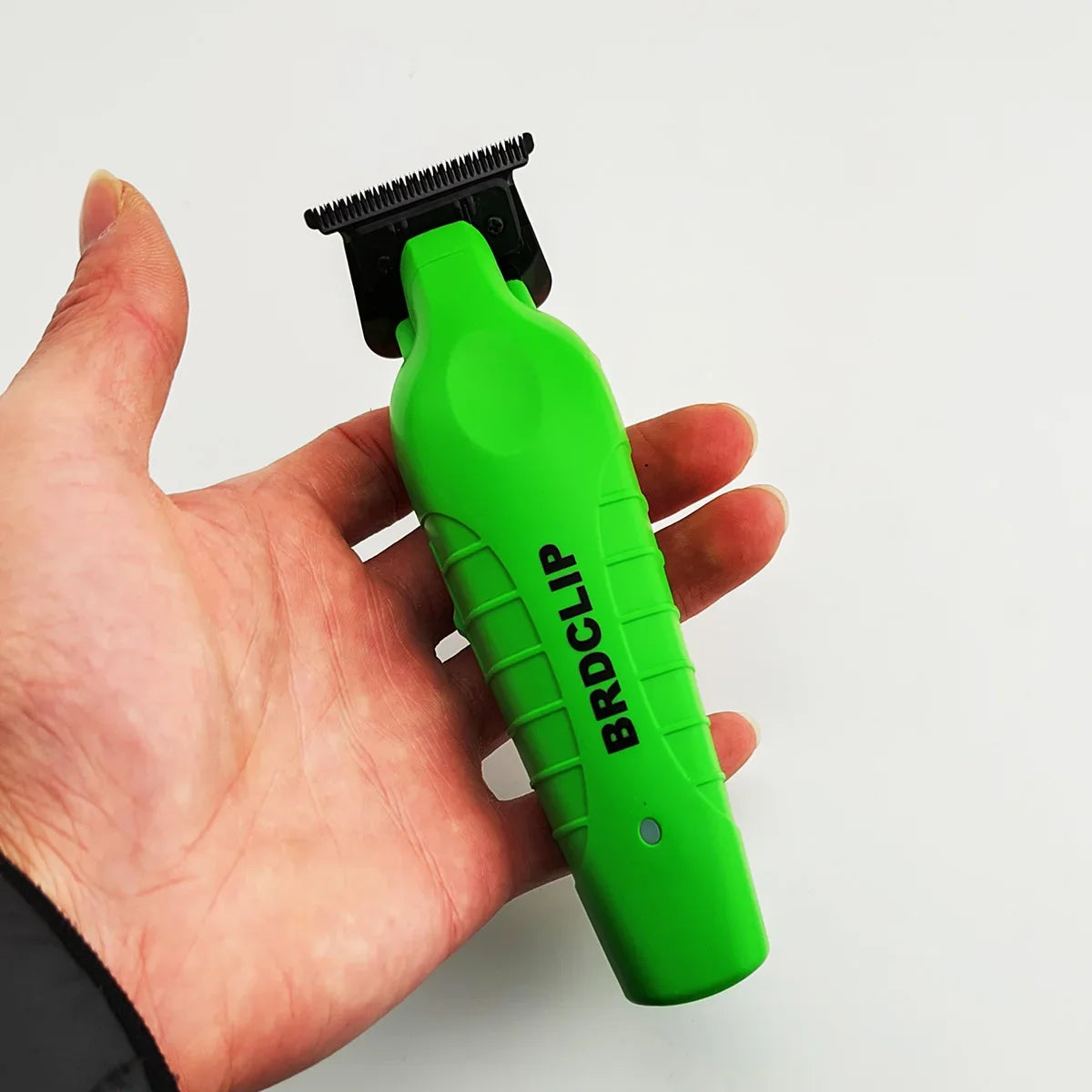 A hand holds a bright green hair clipper with a black comb attachment.