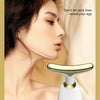 A close-up of a woman's face showing the application of an electric facial lifting and firming massager device.