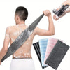 A person is using a black exfoliating loofah on their back, showing the product's texture and use.