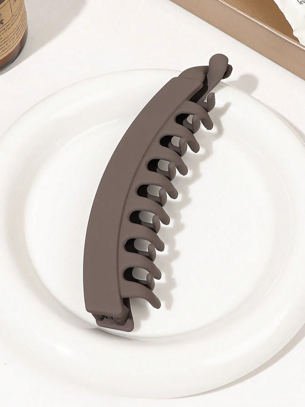 A set of five brown banana hair clips displayed on a white plate.